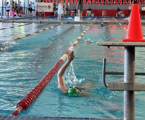 Quinn Ogg '28 swimming backstroke in the warm-up pool.